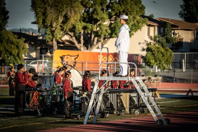 A drum major in white conducting musicians from a podium at the Wilson Field Tournament on October 24, 2026