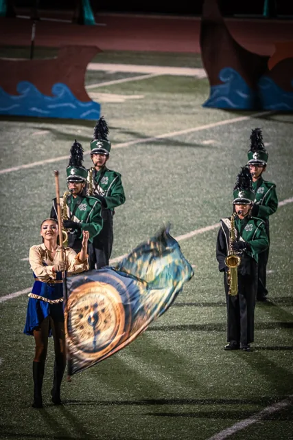 A color guard performer raising a flag beside marching musicians at the Wilson Field Tournament on October 24, 2026