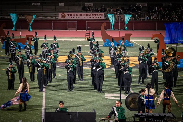 Musicians in green and black performing behind color guard members at the Wilson Field Tournament on October 24, 2026