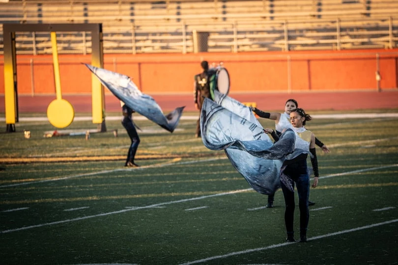 Color guard performers extending blue and silver flags in unison at the Wilson Field Tournament on October 24, 2026